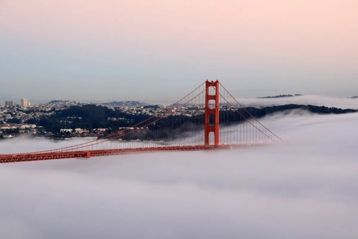 Fog rolling under the Golden Gate Bridge at sunset